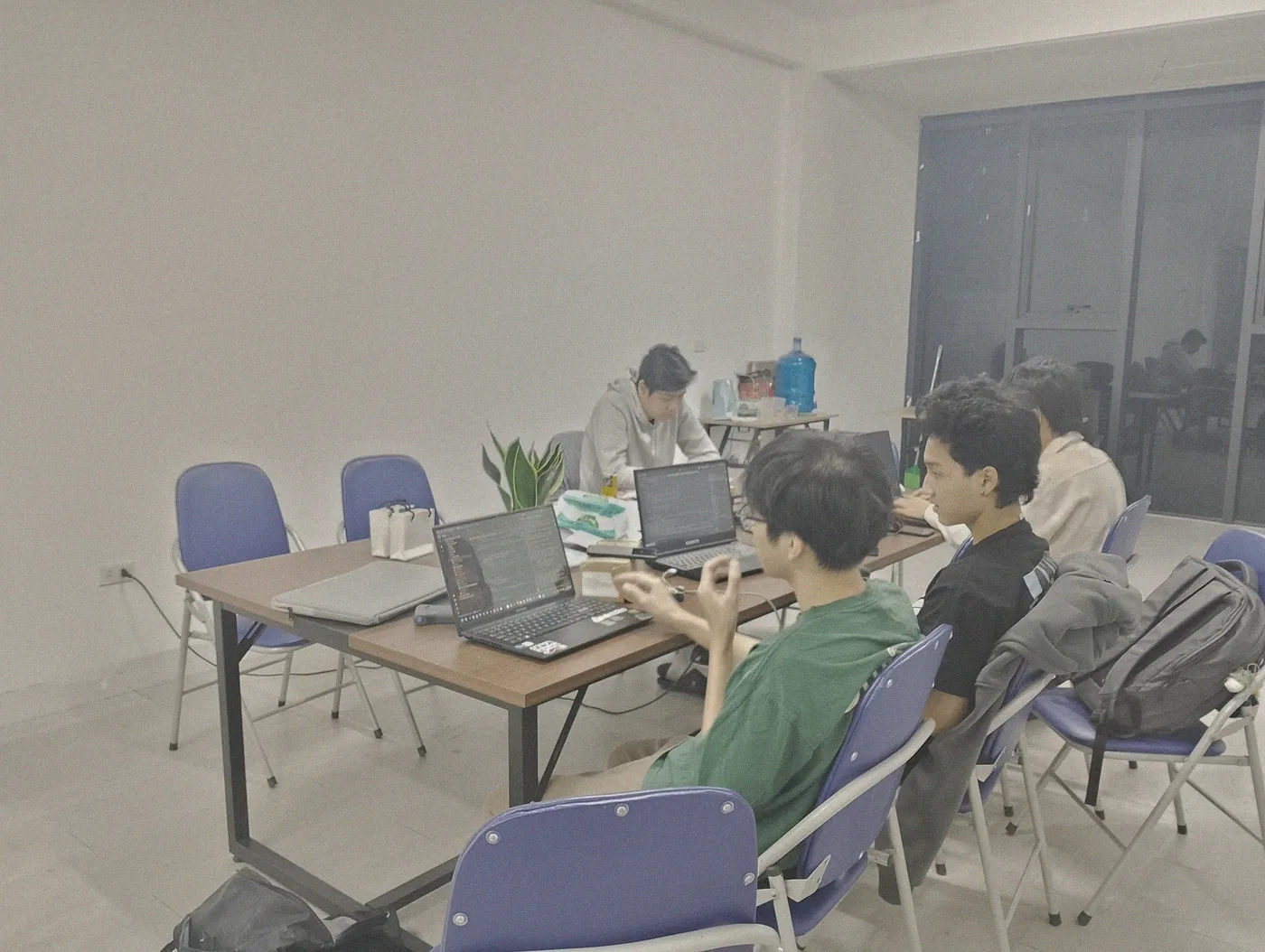 Nhóm SS IT làm việc quanh bàn gỗ, mỗi người một laptop